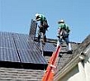 Two workers on roof installing solar panels