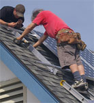 Two workers preparing roof for solar panels