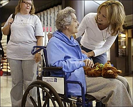 Elder woman in wheelchair smiling at younger woman