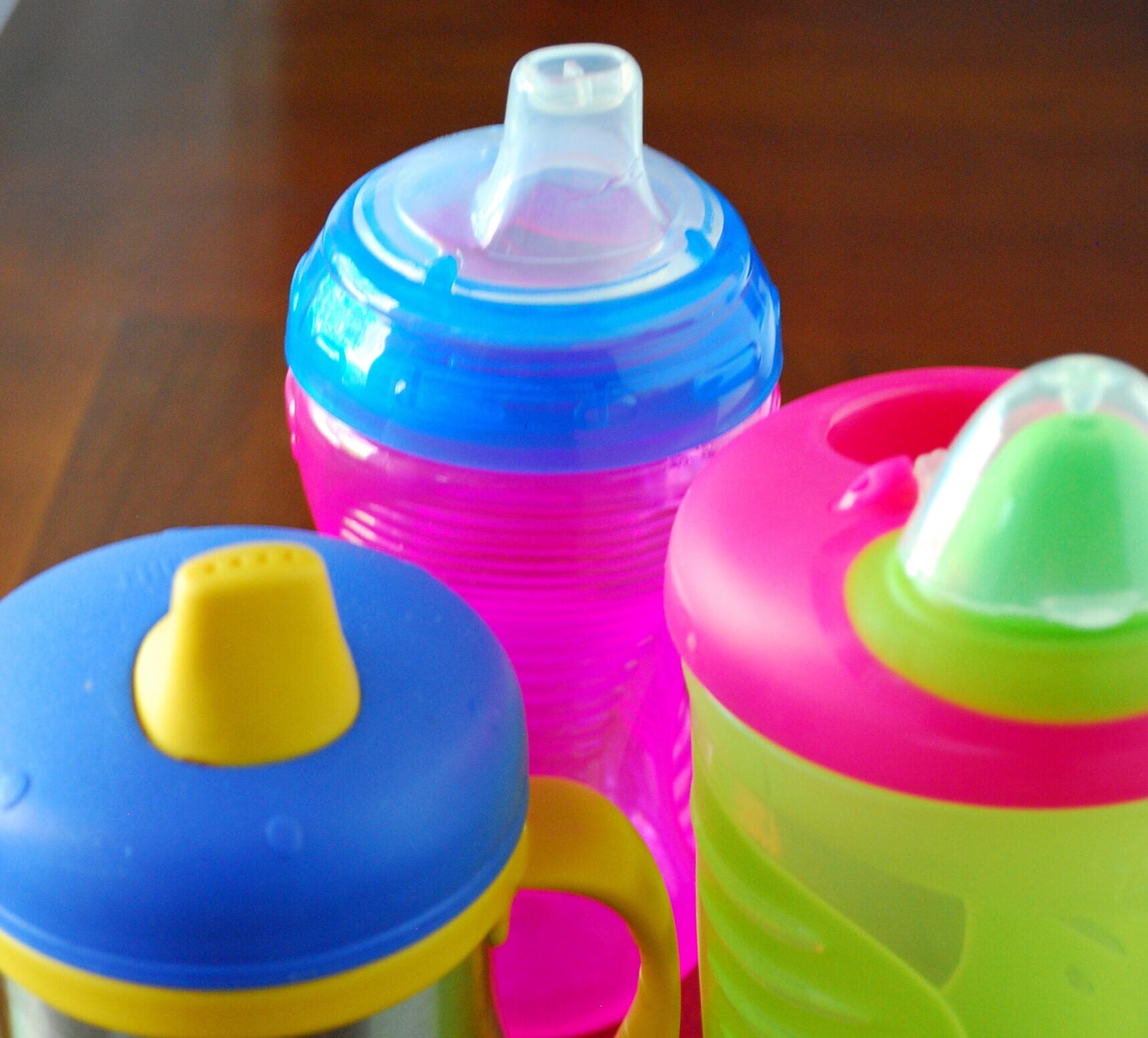 Colorful sippy cups on the table.