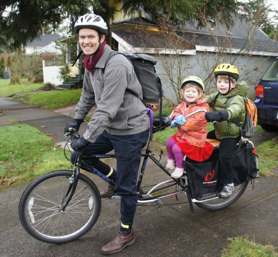 Dad and two small kids on their bike commute to school.