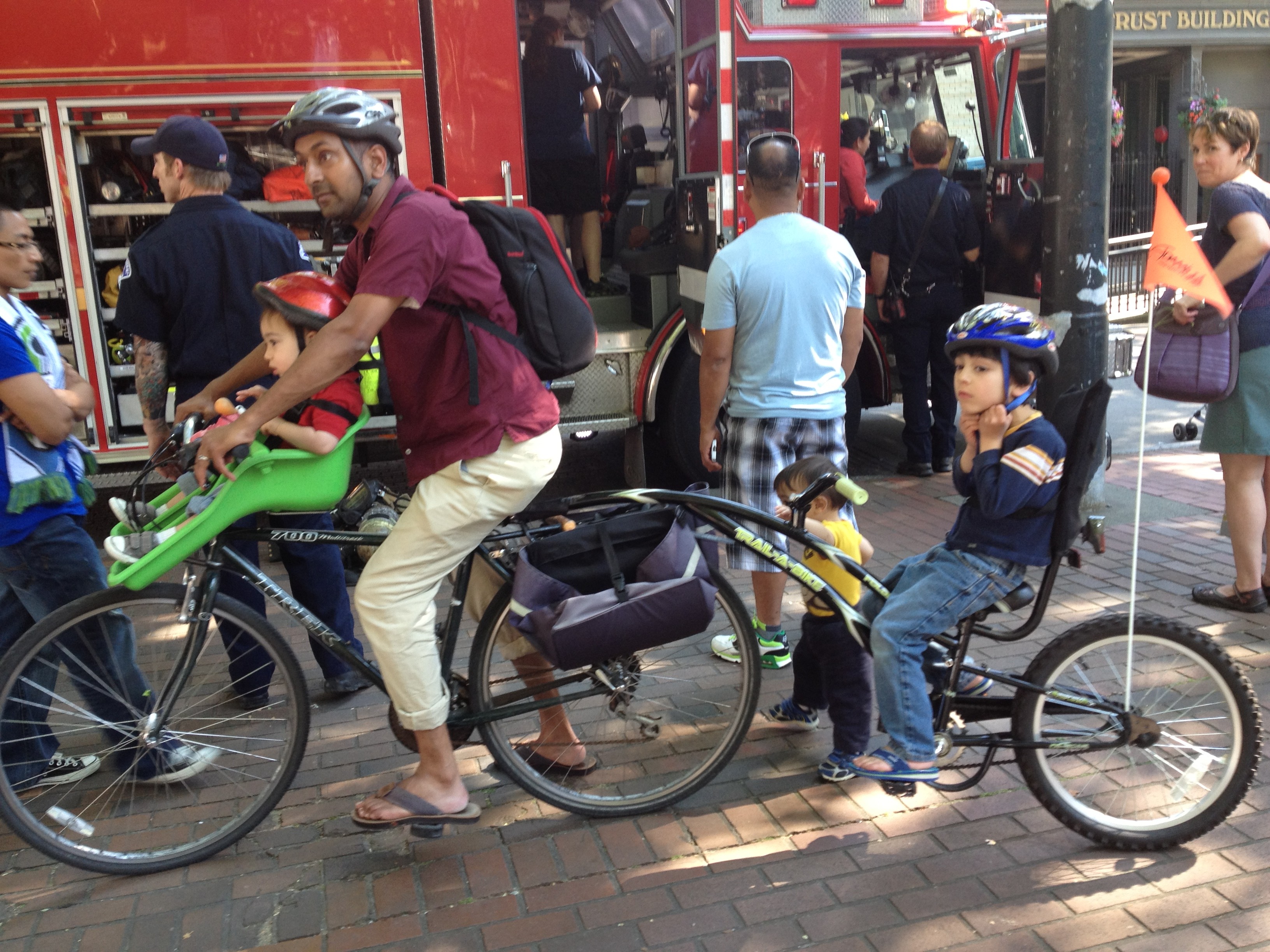 Father and two kids with a handlebar seat and a trail-a-bike!