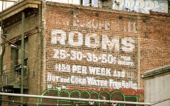 Old sign painted on brick building "Rooms 25 - 50 cents per night, $1.50 per week."