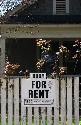 "Room for rent" sign on picket fence in front of house.