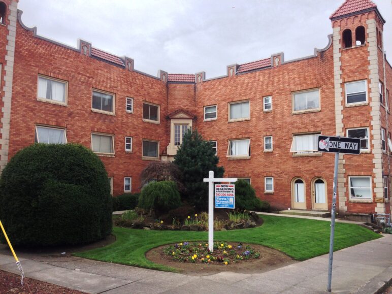 A landscaped courtyard in an L-shaped brick apartment building.