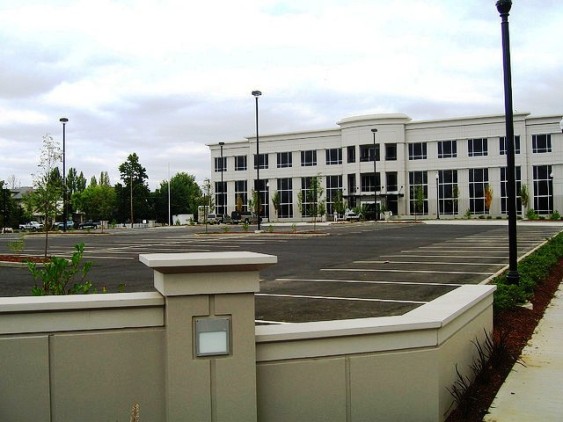 A commercial building set far back from street with parking lot in front.