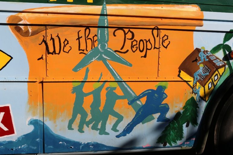 mural with the text "We the People" and silhouettes of people erecting a wind turbine