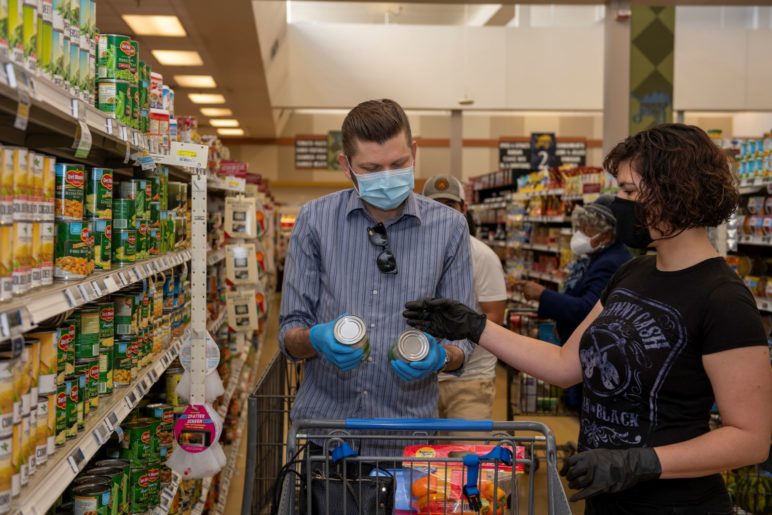 couple shops for groceries in masks and gloves