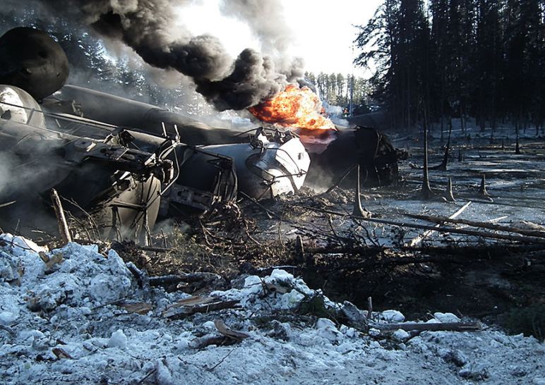 close-up of two oil cars, with a fire in the background
