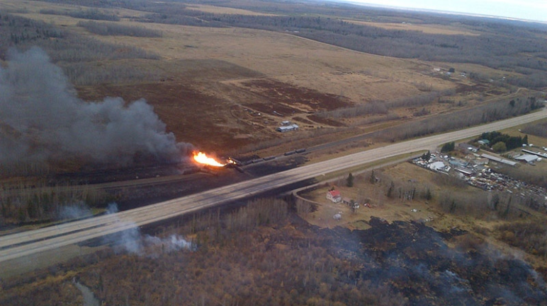 aerial view of an oil train on fire next to a road