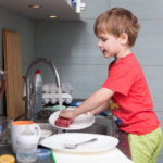 Young boy washing dishes in the kitchen