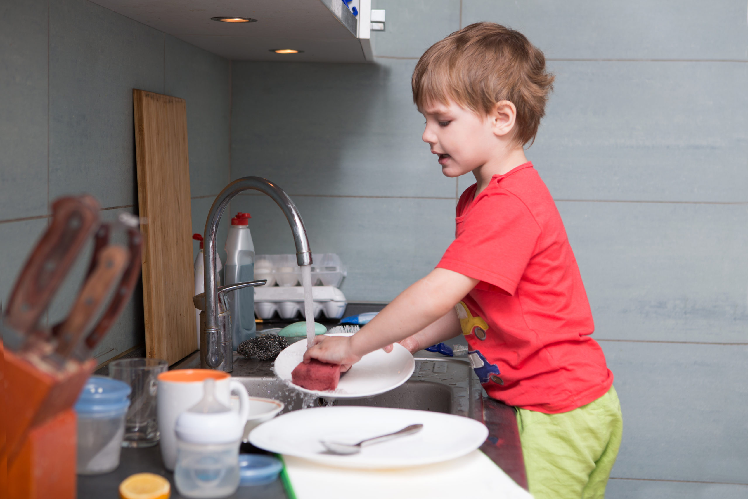 Young boy washing dishes in the kitchen