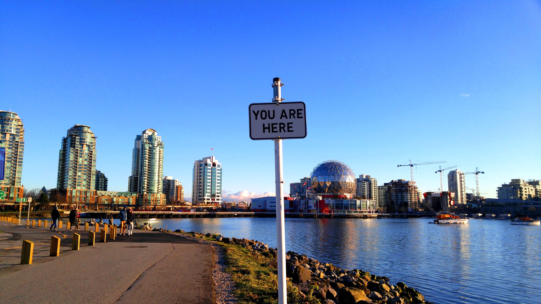 Image of a sign saying "You are here" along a path with downtown Vancouver BC in the background