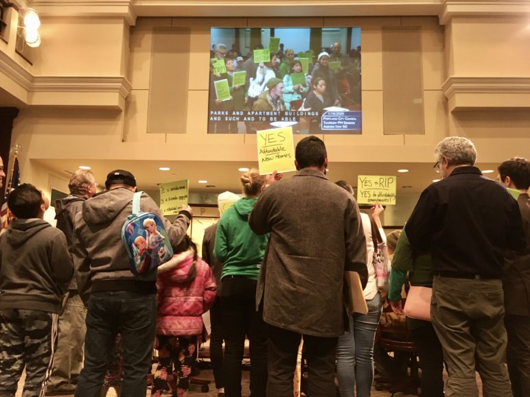 Members of CHAT inside City Council chambers holding yellow signs that say "yes for RIP"