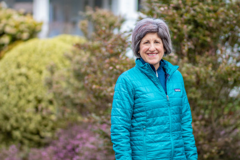Profile photo of Jackie Dingfelder standing in front of a green hedge
