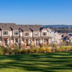 Row of tan townhouses with a green manicured lawn in the foreground, Mt. Hood in the background to the right