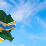 Portland city flag against a blue sky with cloud wisps
