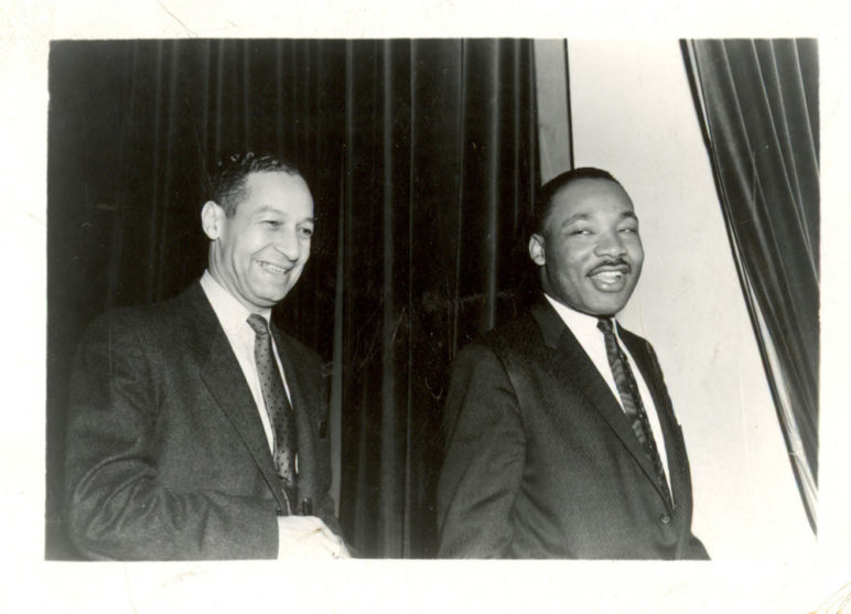 Black and white photo of Ted Berry walking next to Dr. Martin Luther King, Jr. Both are smiling.