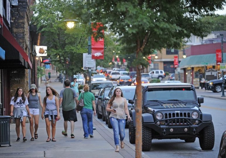 Photo of Dickson Street in Fayetteville, showcasing busy and walkable sidewalks with pedestrians 
