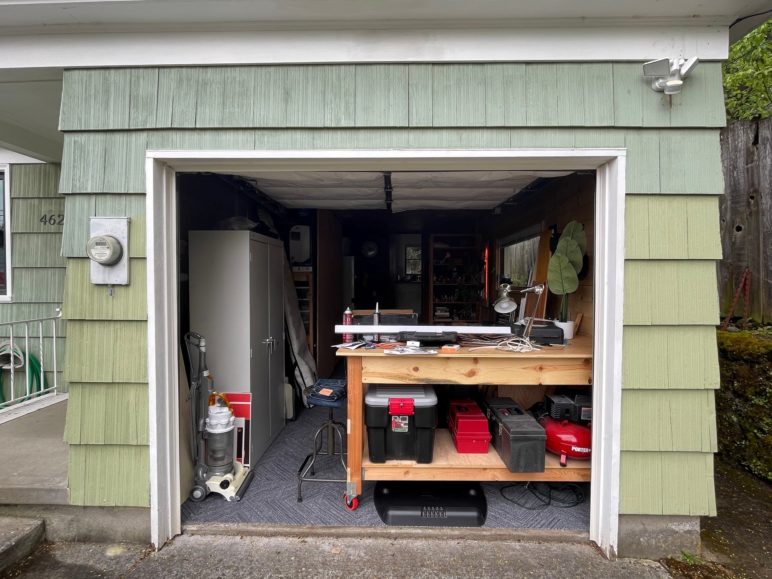Another open garage door featuring what is now a converted workshop instead of car storage.
