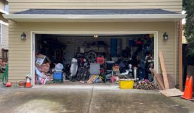 Photo of an open garage door featuring an impressive collection of vintage clutter