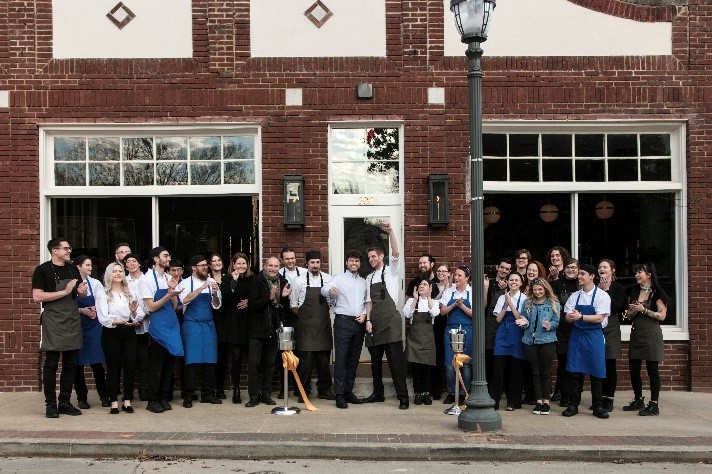 Employees celebrate the opening of Atlas the Restaurant in a newly renovated historic building in Fayetteville, Arkansas. Until Fayetteville removed commercial parking mandates in 2015, it would have been illegal to use the building as a restaurant without special permission. Photo: Atlas the Restaurant. Used with permission. 