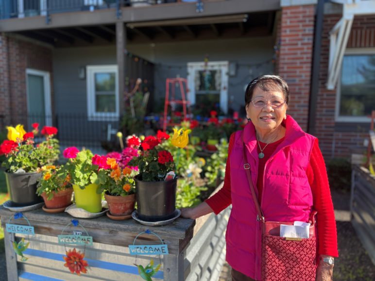 Avelina Cabantan stands alongside her raised flower bed, at Orchards at Orenco. Photo by Catie Gould. 