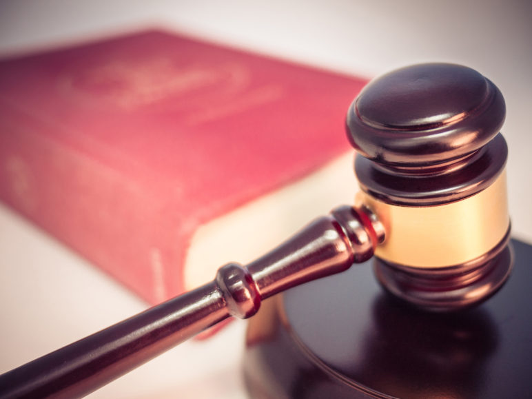 Photo of a gavel and law book blurred in the background