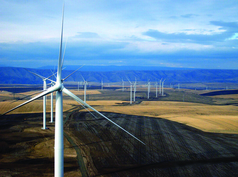Photo of wind turbines over flat fields.