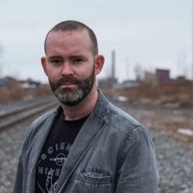 Profile of a bearded male in a rail track background