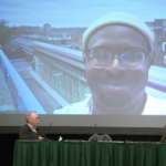 Jarred Johnson of TransitMatters (on screen) talks about Massachusetts’s multifamily housing by right legislation with moderator Ben Crowther (left), Joe Cortright of City Observatory (center), and Ben Holland of RMI (right) (screenshot from video of session).