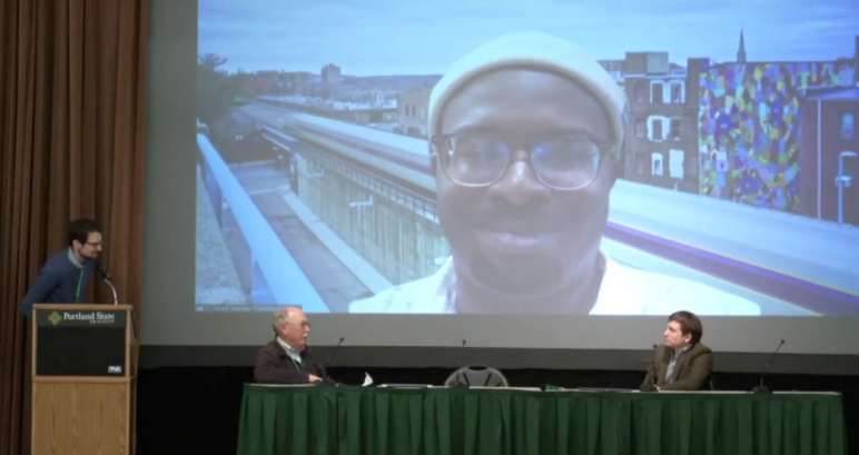 Jarred Johnson of TransitMatters (on screen) talks about Massachusetts’s multifamily housing by right legislation with moderator Ben Crowther (left), Joe Cortright of City Observatory (center), and Ben Holland of RMI (right) (screenshot from video of session).