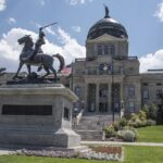 Photo of the Montana State Capitol Building, with a statue of a man on horseback in front.