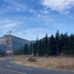 Transmission lines across the highway with a mountain in the background