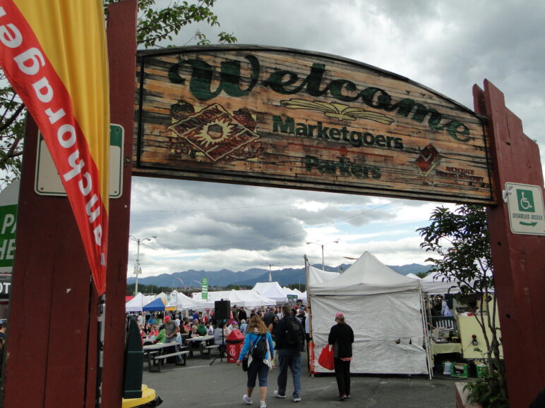Large wooden "Welcome" sign leading to the Anchorage market held in a parking lot