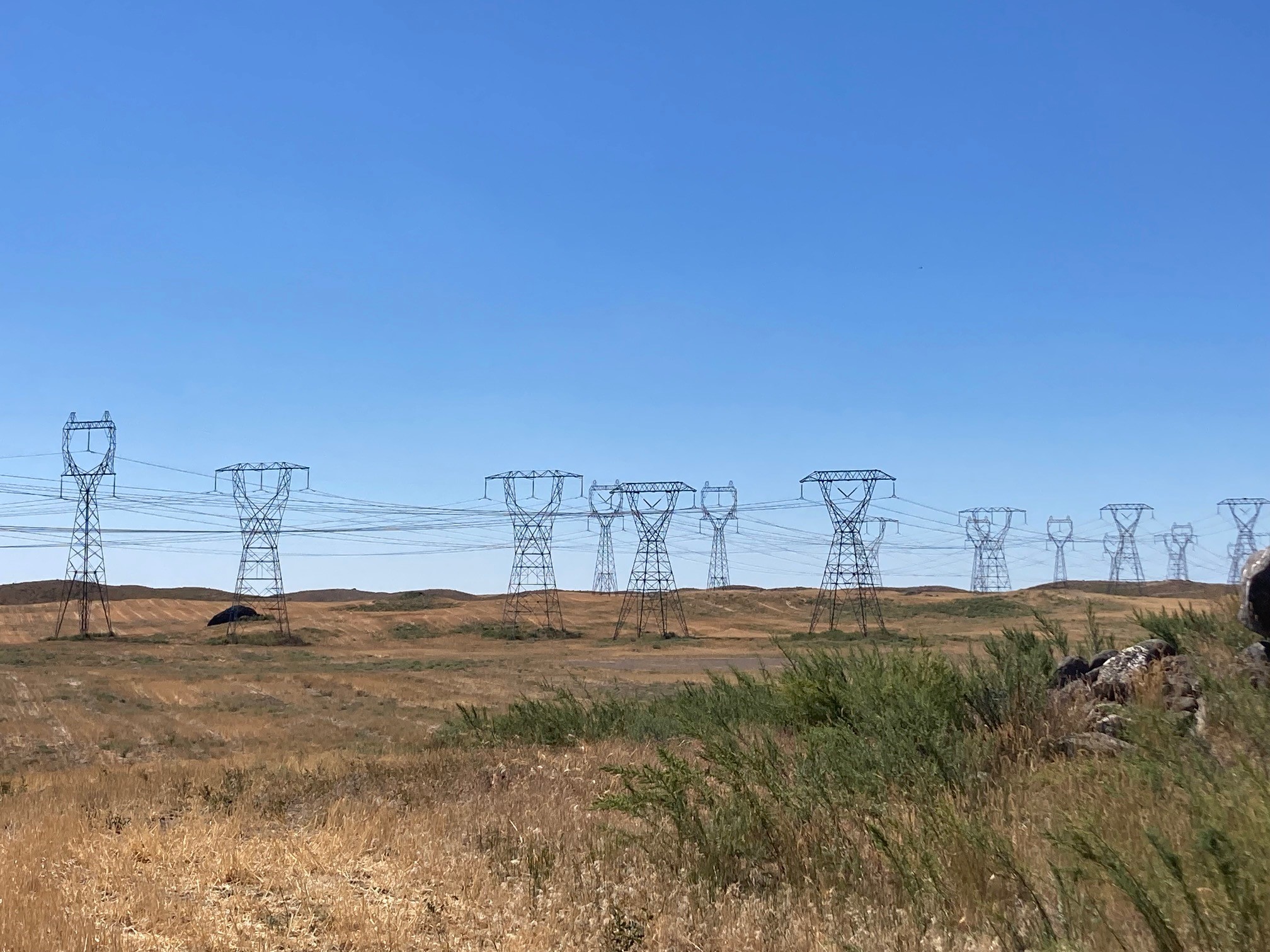 Photo of transmission lines on a clear day over dry fields