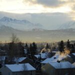 Mountains behind Anchorage, AK while snow-capped roofs of a neighborhood can be seen in the foreground