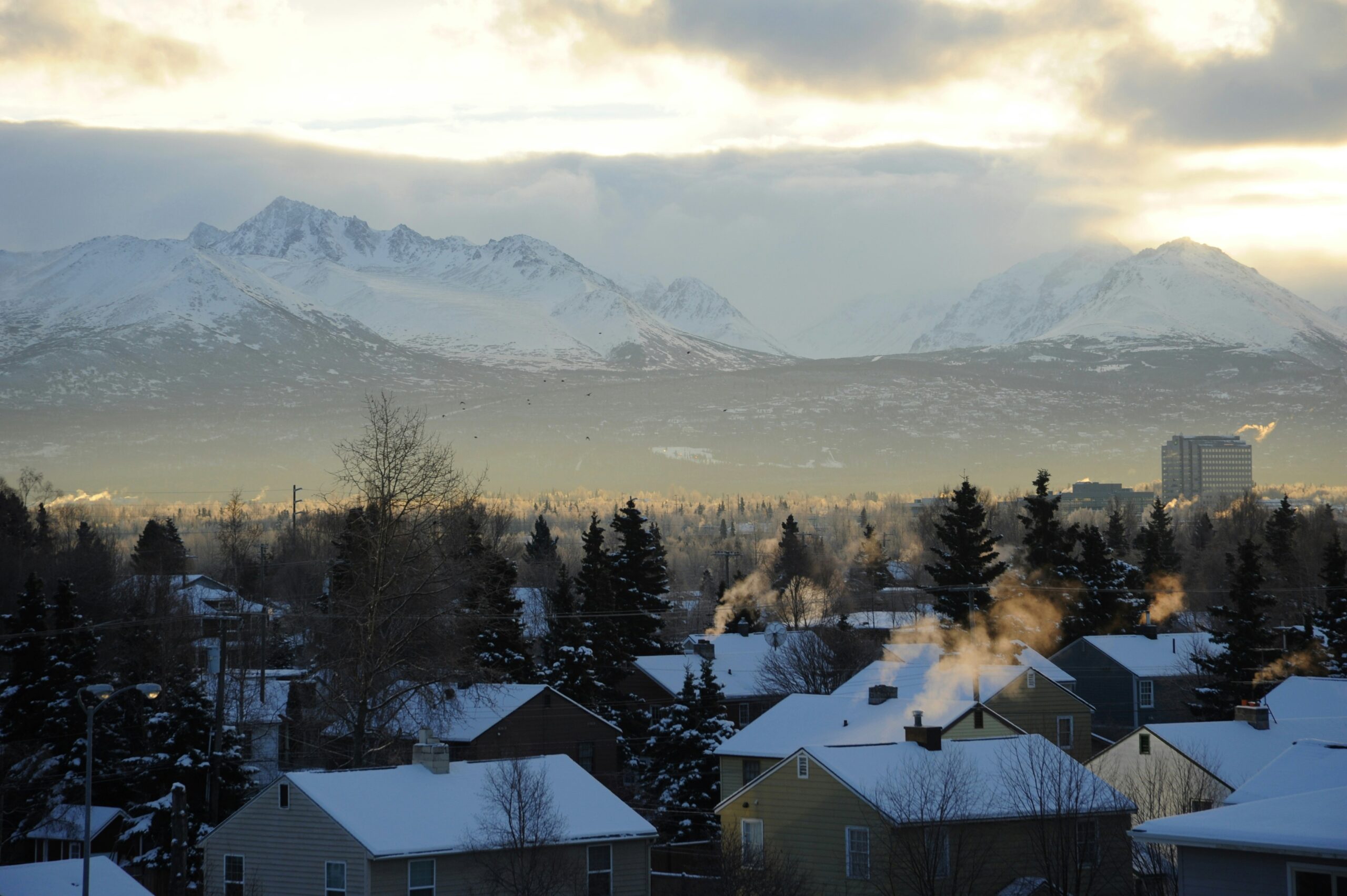 Mountains behind Anchorage, AK while snow-capped roofs of a neighborhood can be seen in the foreground