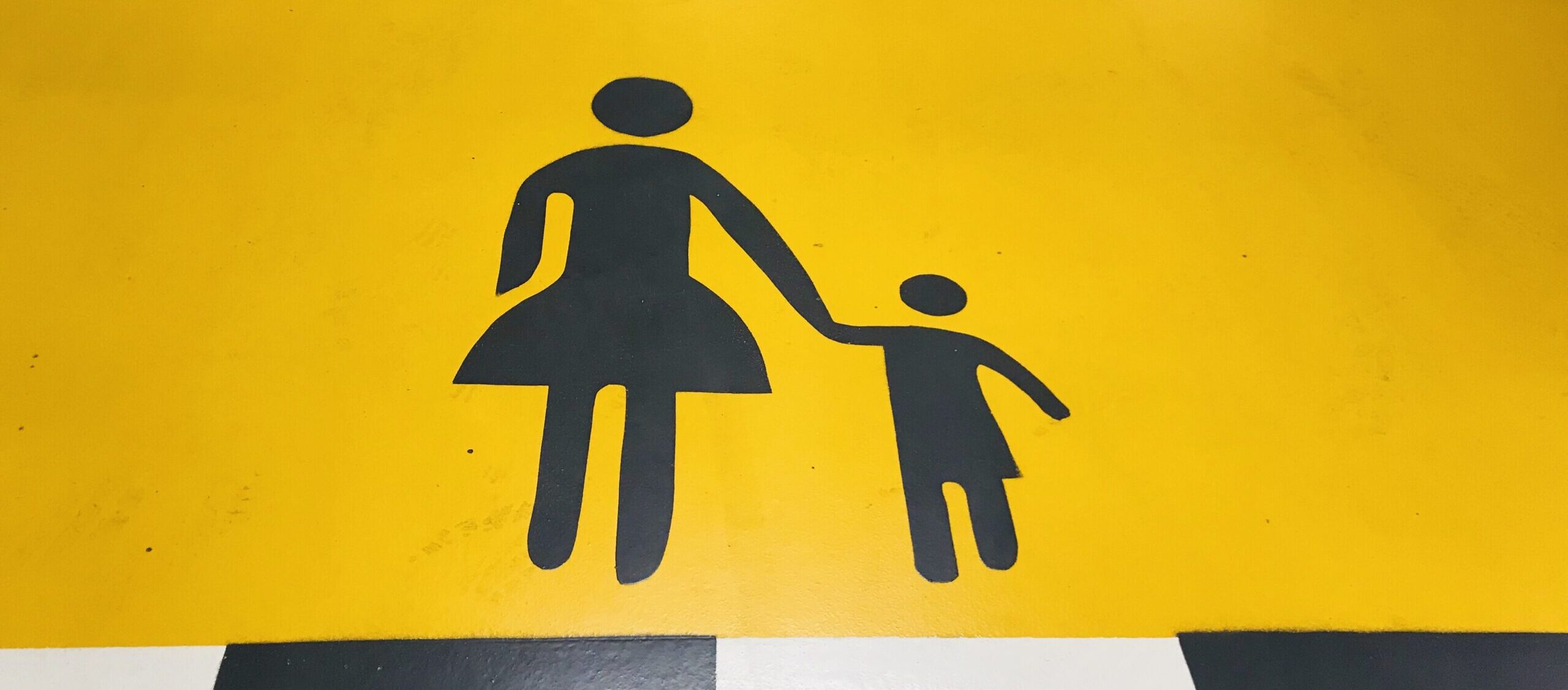 Photo of a painted floor with a yellow backdrop, and a symbol of a parent holding a child's hand in the center.