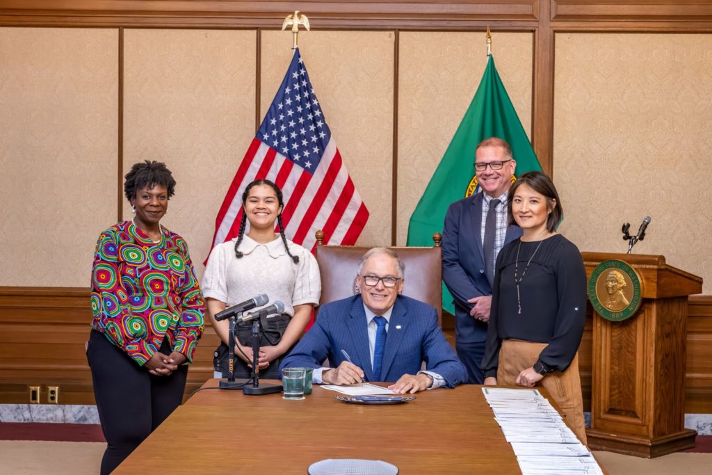 Photo of Governor Inslee signing HB1998 into law, with bill sponsor Rep. Gregerson (far right).