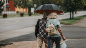 Two elderly women are walking in the rain