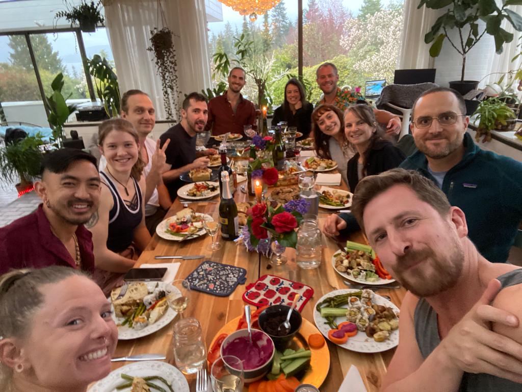 Group of housemates sharing dinner at a long table in their Vancouver, BC, home.