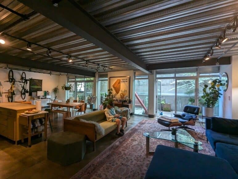 East Union Lofts, interior. Photograph by author. Interior  photo of a large, open space for a living area, kitchen area, and workshop area. Large windows leading out make up one entire wall.