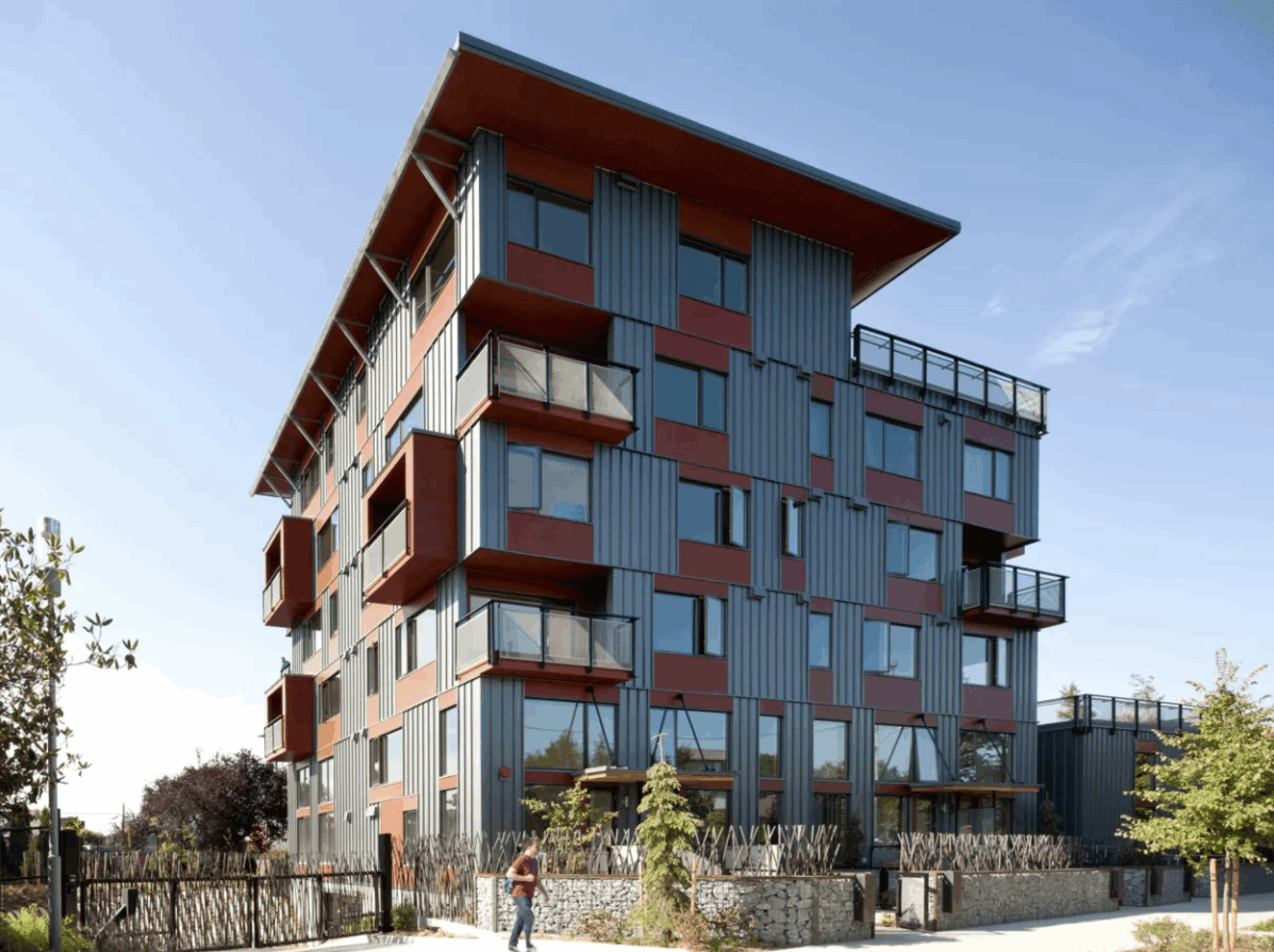 The Greenfire campus. Photograph courtesy of Johnston Architects. Photo of a modern multi-unit apartment building on a sunny day. Wide windows and several private and common decks can be seen.