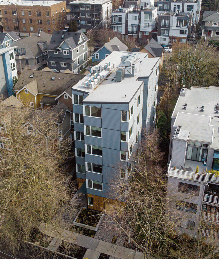 Photograph courtesy of Habitat for Humanity Seattle–King & Kittitas Counties. Aerial photo of a narrow multi-unit building in the city, among trees in the city in autumn.
