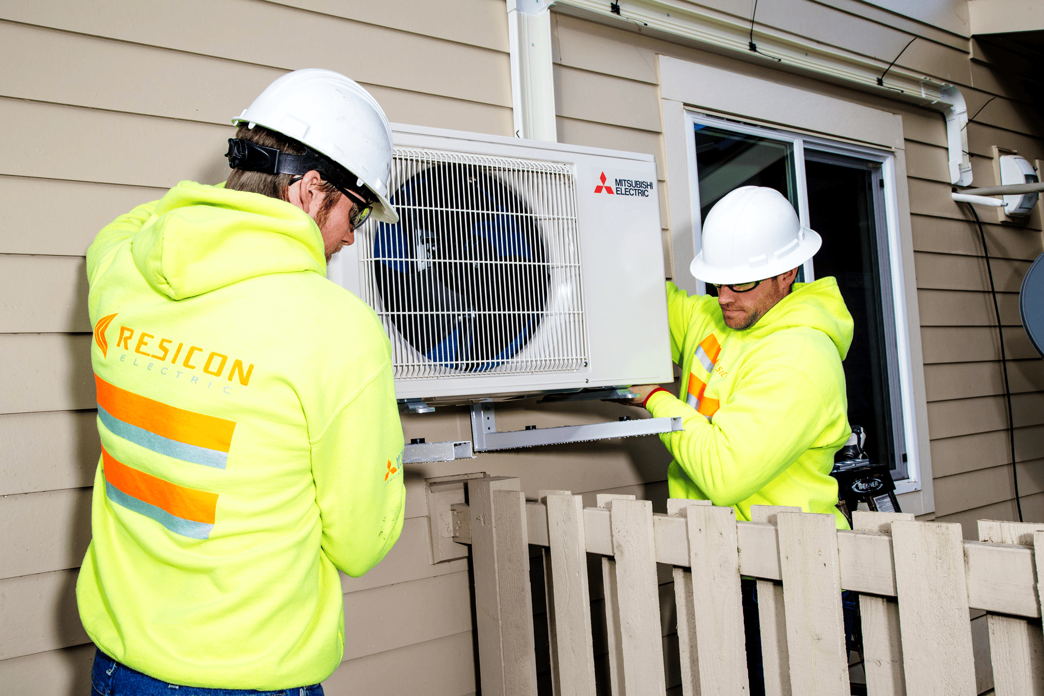 Construction workers, Jake Holmgren and Jason Clement, help install new heat pumps for residents in South Seattle.