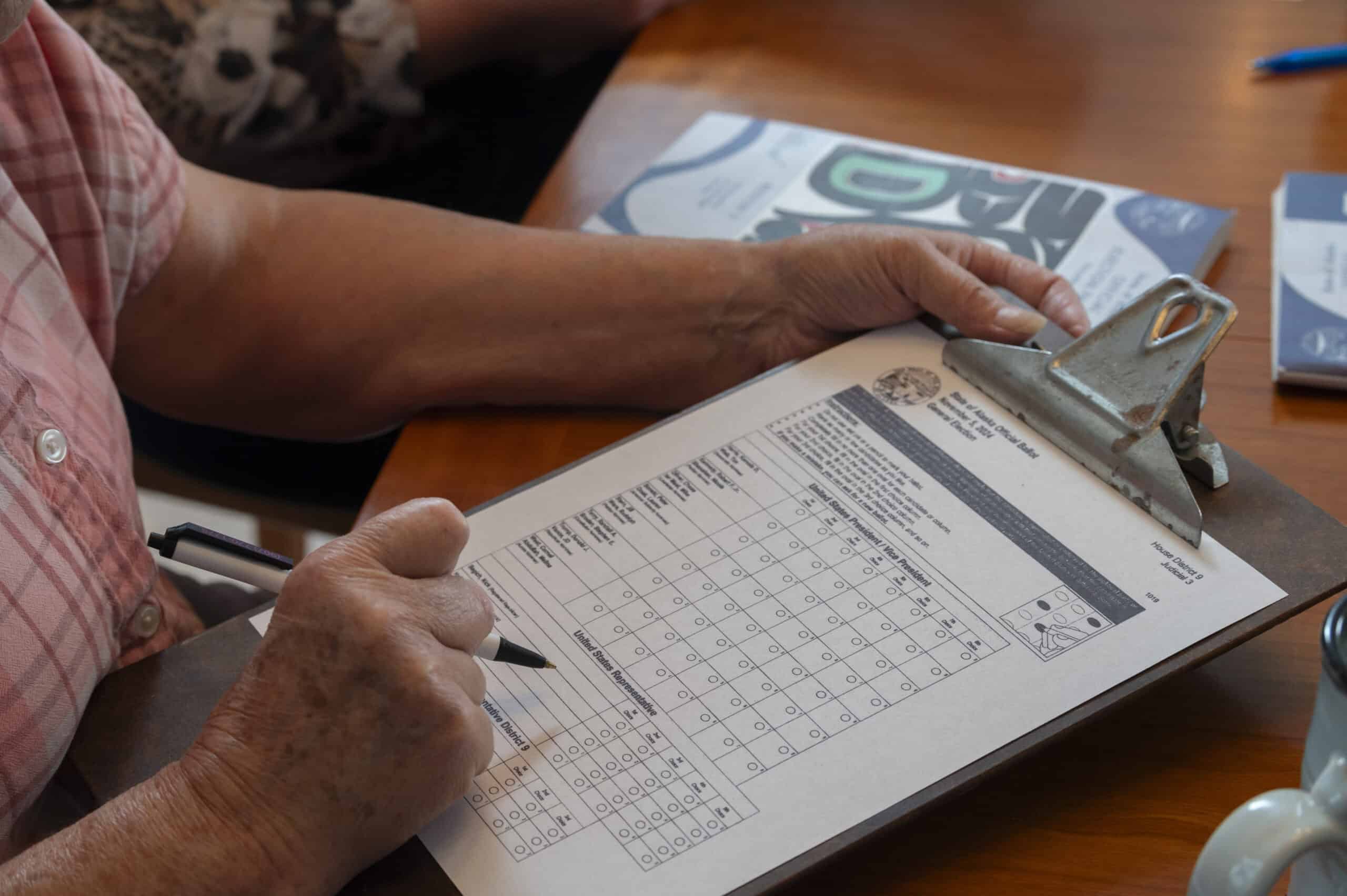 A voter considers her ballot as she votes from home in the 2024 presidential election, in Anchorage, Alaska. Photo by Michael Dinneen, all rights reserved.