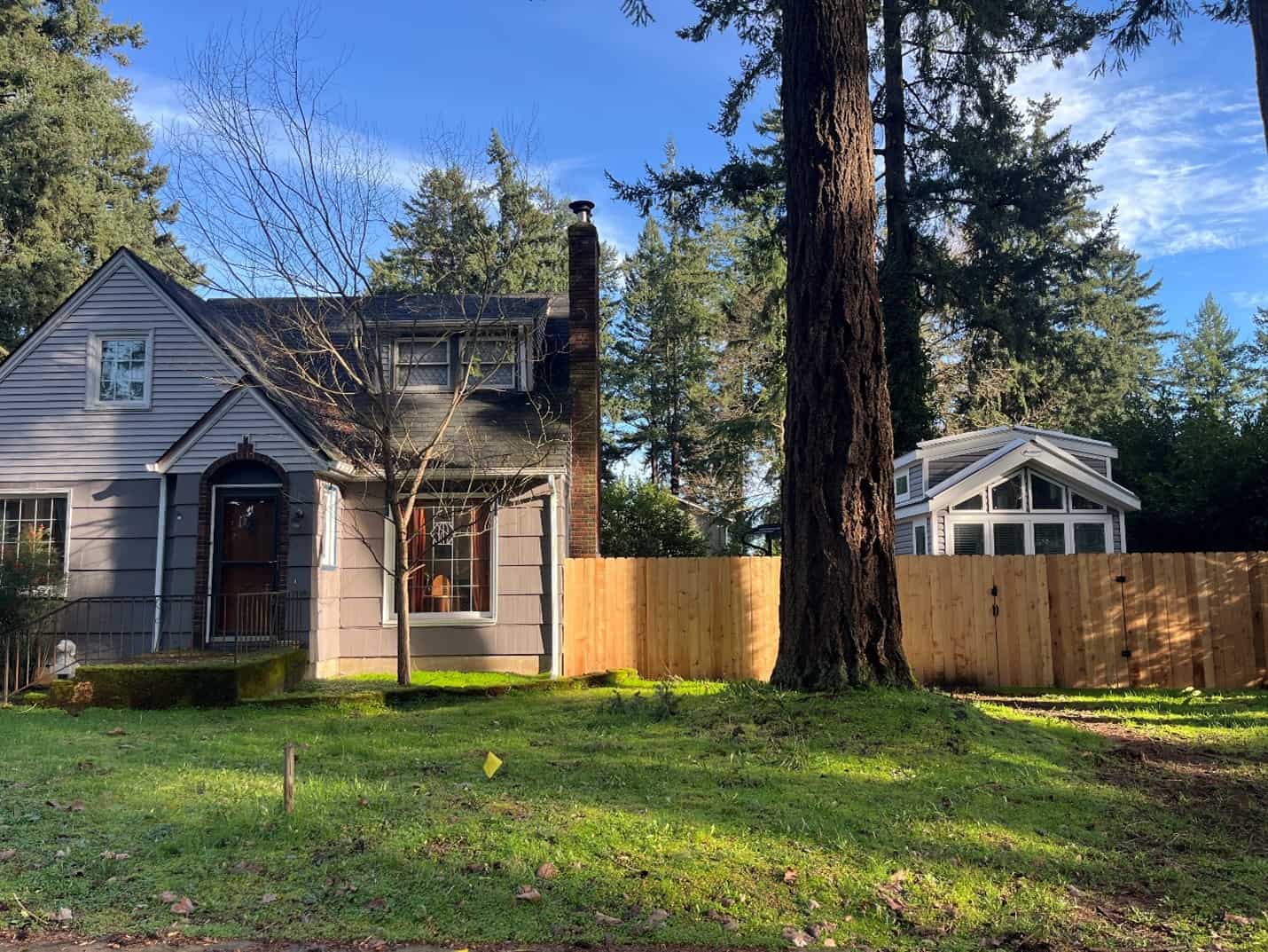 A cozy tiny home on wheels, aka mobile dwelling unit (MDU), peeks out from behind a single-detached home in Portland, Oregon. Photo by Catie Gould.