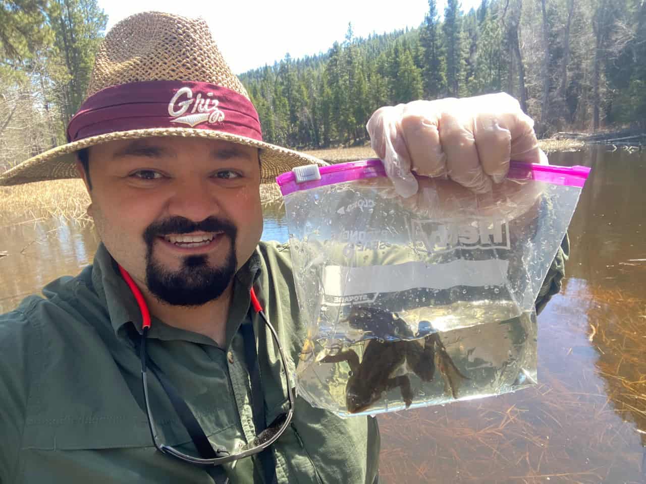 Erim at the river, holding a little baggie with a frog hopping about