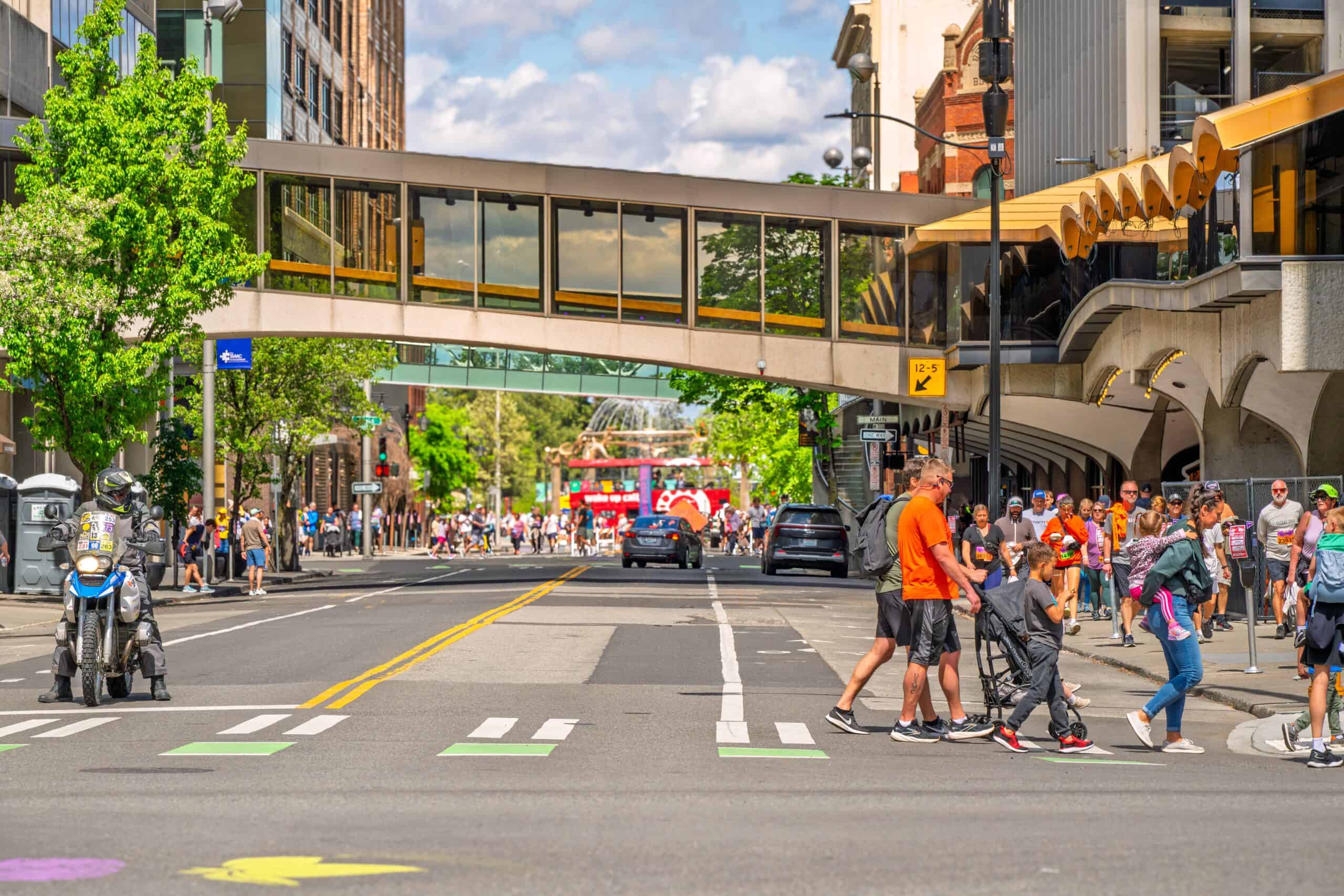 Pedestrians and participants fill the streets of downtown Spokane at the end of the 12K Lilac Bloomsday Run with Riverfront Park in the distance.